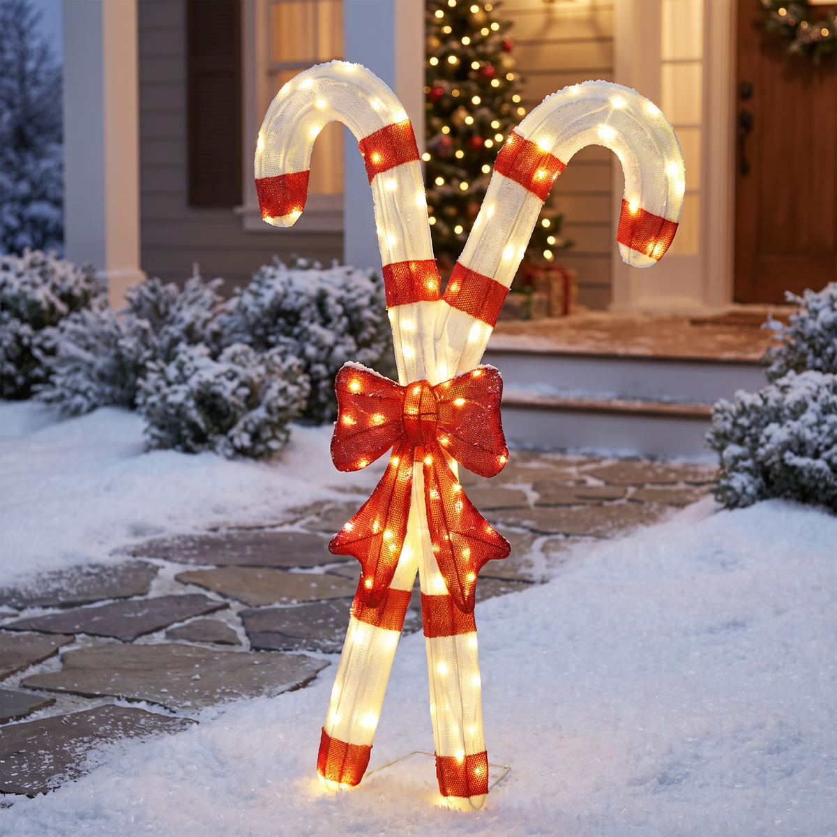 Lighted candy cane decorations on a snowy front lawn